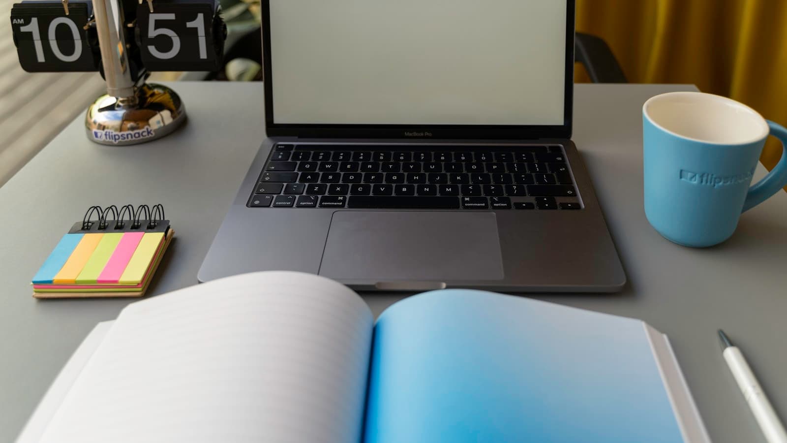 Notebook aberto e uma xícara sobre a mesa